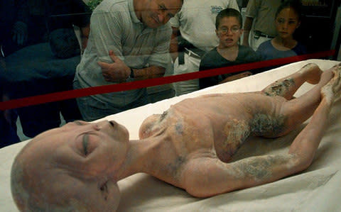 Visitors to the International UFO Museum in Roswell, New Mexico examine a glass-encased alien prop used in the movie "Roswell"