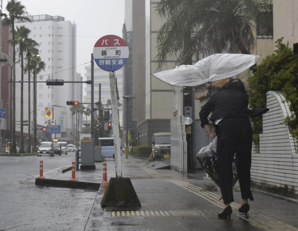 A pedestrian tries to keep an umbrella damaged in a storm in Miyazaki, southern Japan, Tueaday, Aug. 8, 2023. Early Tuesday morning, the storm was centered 350 kilometers (217 miles) south of Kagoshima, a city on the southwestern tip of Japan’s main southern island of Kyushu and southwest of Miyazaki. Khanun produced winds of 108 kph (67 mph) with gusts to 144 kph (89 mph) and was slowly moving north, the Japan Meteorological Agency reported. (Kyodo News via AP)