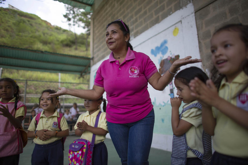 In this Oct. 7, 2019 photo, teacher Daixy Aguero leads her students during an activity at a school in Caracas, Venezuela. Public school teachers like Aguero started out earning the minimum wage equal to a few U.S. dollars a month, while it doubles and triples with years of experience. However, teachers say the government doesn't honor their agreement, leaving them broke. (AP Photo/Ariana Cubillos)