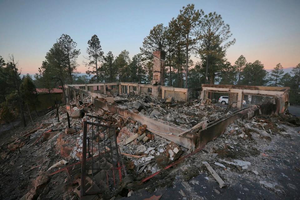 A two-story house continues to smolder following the McBride Fire in Ruidoso, New Mexico, on Thursday, April 14, 2022.   Authorities say firefighters have kept a wind-driven blaze from pushing further into a mountain community in the southern part of the state.