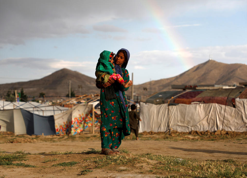 Una niña afgana lleva en brazos a un bebé en un campo de refugiados. REUTERS/Omar Sobhani