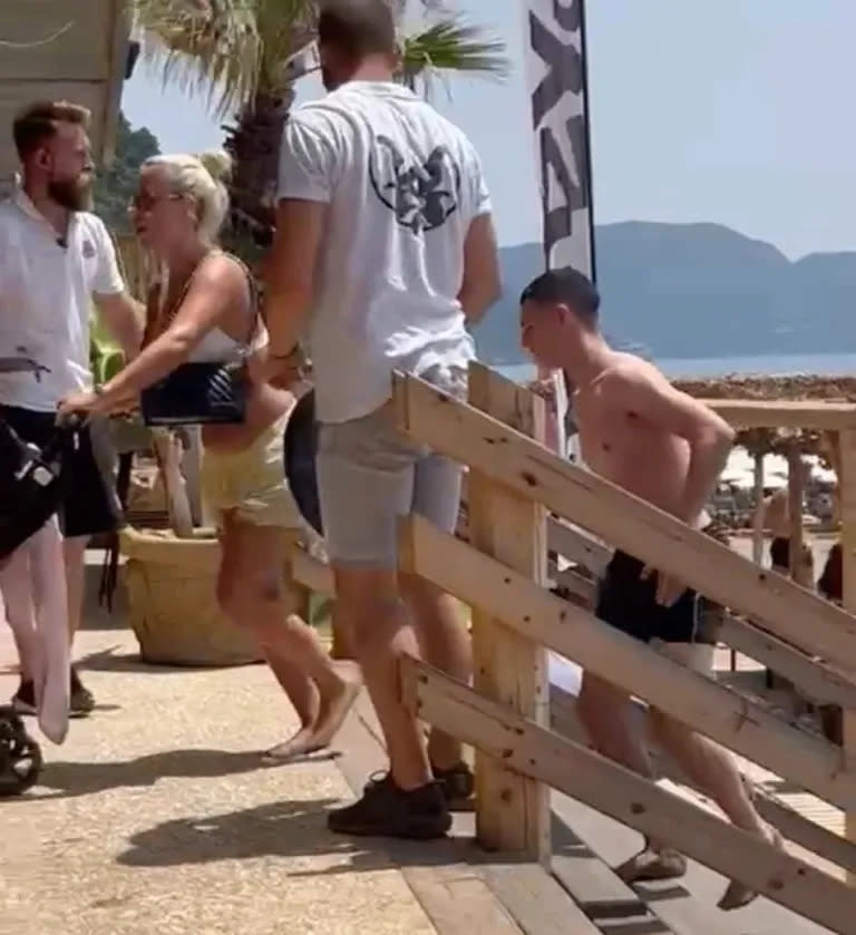 Phil Foden y Rebecca Cooke salen de la playa escoltados por efectivos de seguridad (Foto: Captura de video)