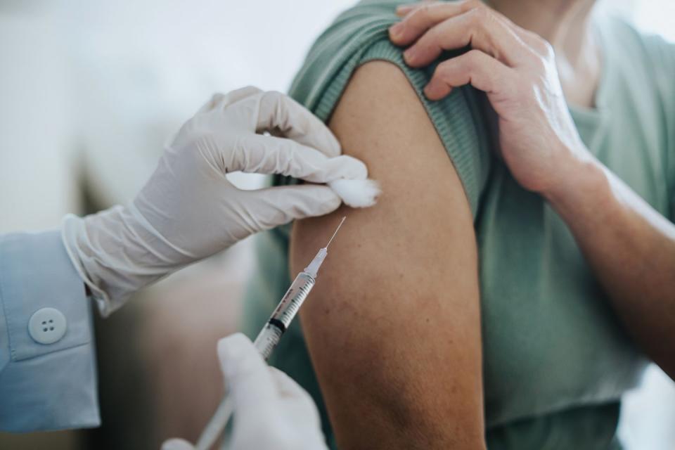 close up of senior asian woman getting covid 19 vaccine in arm for coronavirus immunization by a doctor at hospital elderly healthcare and illness prevention concept