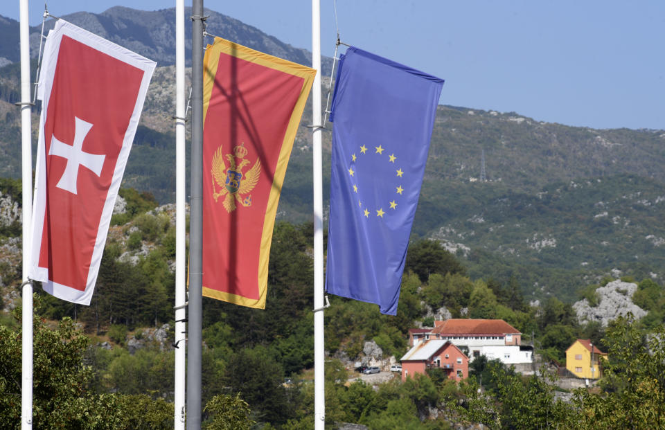 Flags flew at half-mast in front of the site of the attack in Cetinje, some 30 km west of Podgorica, Montenegro, Saturday, Aug. 13, 2022. A man went on a shooting rampage in the streets of a western Montenegro city Friday, killing multiple people, before being shot dead by a passerby, officials said. (AP Photo/Risto Bozovic)