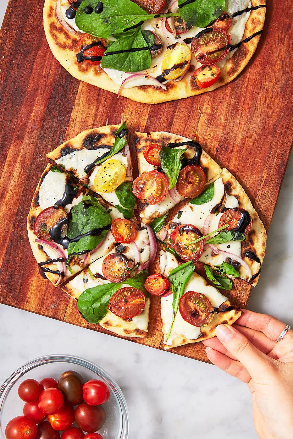 two flatbread pizzas on a wooden cutting board