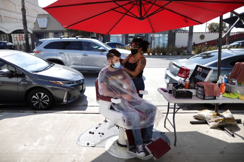 Lulu Castillo, 26, cuts the hair of Joe Nasr, 35, on the street outside Active Barbers, amid the global outbreak of the coronavirus disease (COVID-19), in Santa Monica