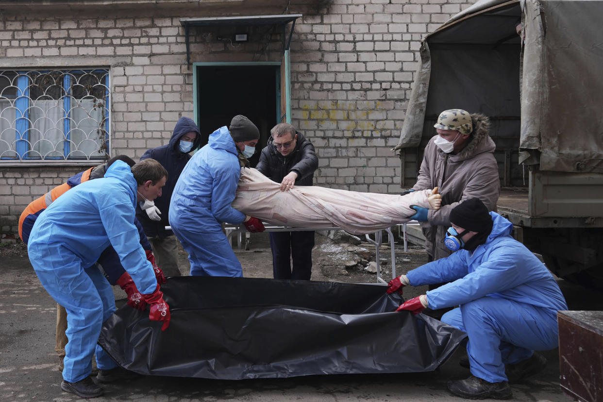 Mortuary workers move a dead body into a plastic bag in outskirts of Mariupol on Wednesday. (Evgeniy Maloletka/AP) 