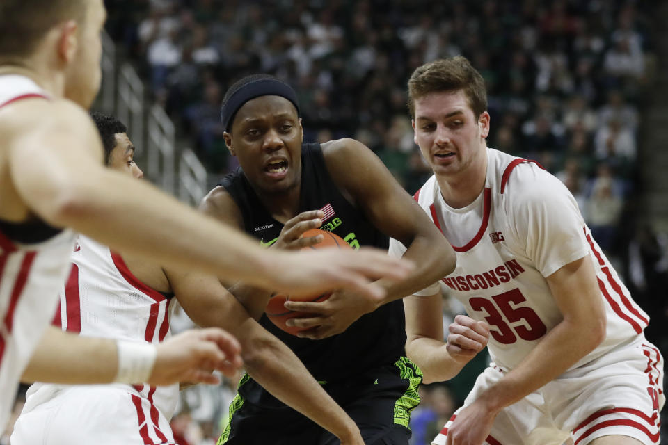 Michigan State guard Cassius Winston, center, cuts through the defense of Wisconsin guard D'Mitrik Trice (0) and forward Nate Reuvers (35) during the second half of an NCAA college basketball game, Friday, Jan. 17, 2020, in East Lansing, Mich. (AP Photo/Carlos Osorio)