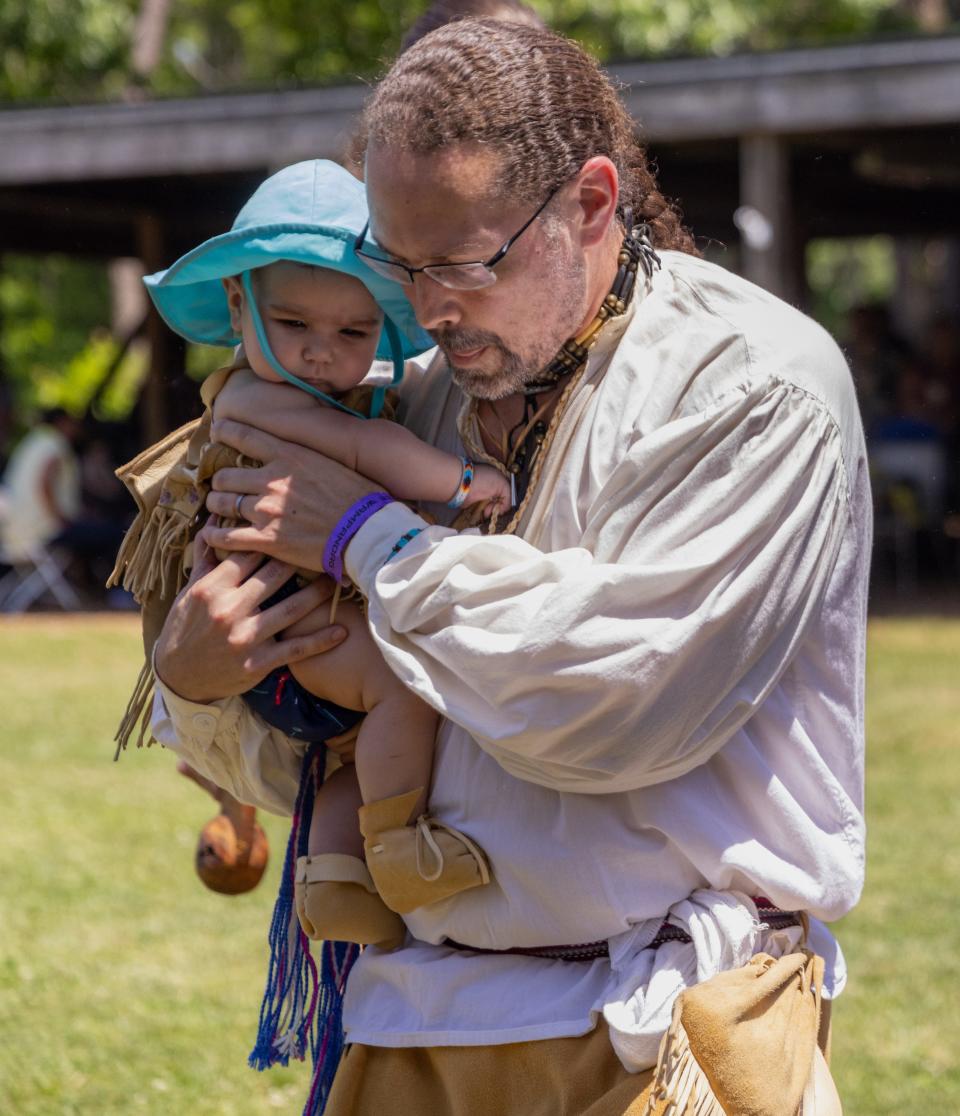 Casey Thornbrugh carries his daughter Marianna Thornbrugh, who is six months, in the opening ceremony at the Wampanoag Powwow Grounds in Mashpee on Friday. 
Sophie Proe/Cape Cod Times