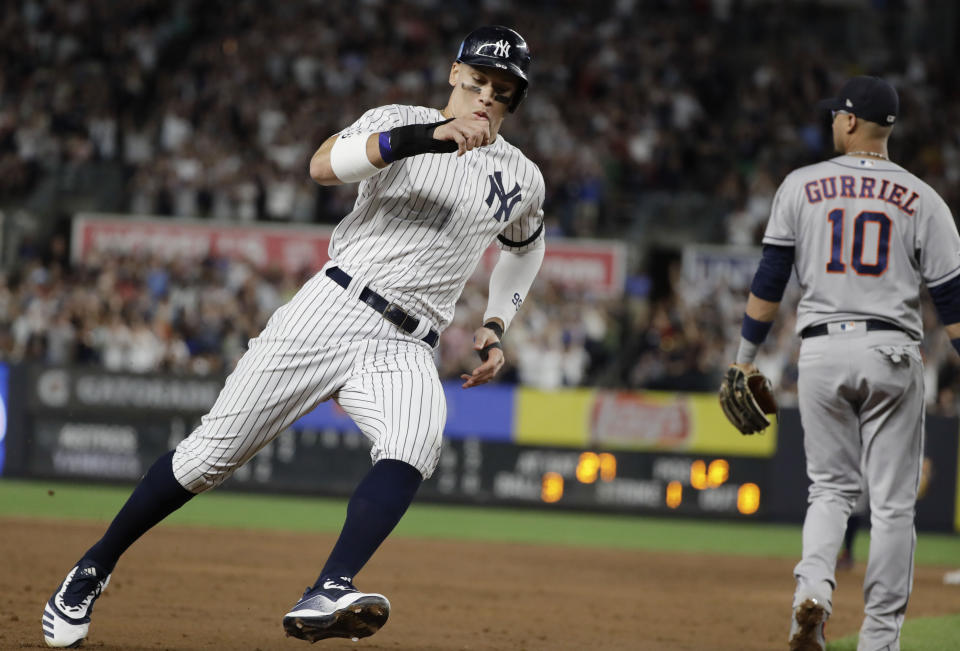 New York Yankees' Aaron Judge, left, runs past Houston Astros' Yuli Gurriel on the way to scoring on a single by Giancarlo Stanton during the sixth inning of a baseball game Saturday, June 22, 2019, in New York. (AP Photo/Frank Franklin II)