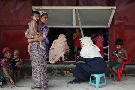 Rohingya women and their children wait to receive treatment at a makeshift clinic in the Thet Kae Pyin camp for internally displaced people in Sittwe, Rakhine state, April 24, 2014. REUTERS/Minzayar