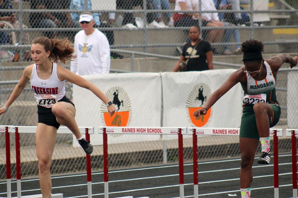 Creekside's Kate Franklin (2723) and Mandarin's Elaine Williams (3232) clear hurdles during the girls 300-meter hurdles at the Bob Hayes Invitational Track Meet on March 19, 2022.