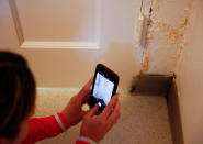 FILE PHOTO: Leigh Tuttle takes a picture of pale orange mold behind the door of the guest bathroom in the basement of Krista Lindholm's house at Joint Base Lewis-McChord, Washington, U.S. May 13, 2019. REUTERS/Lindsey Wasson