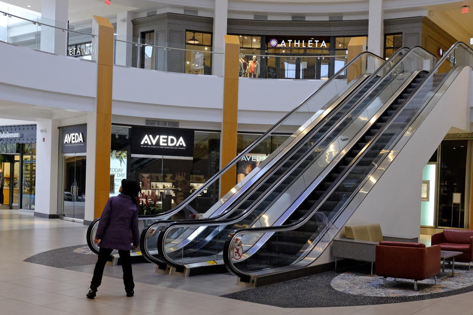 A visitor looks down an empty hallway at The Fashion Mall at Keystone, Wednesday, March 18, 2020, in Indianapolis. Simon Property Group, the largest owner of shopping malls in the nation, is closing all of its malls and retail properties because of the coronavirus outbreak. (AP Photo/Darron Cummings)