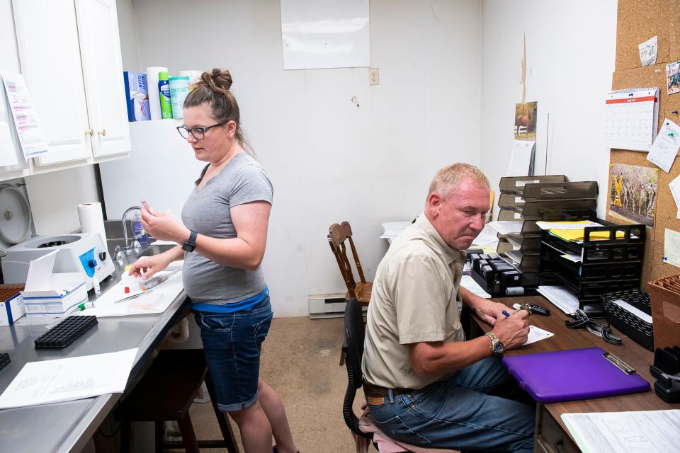 Dr. Jim Holt fills out paperwork inside his office trailer on a busy Monday morning at New Holland Sales Stables in Lancaster County last summer. His lab technician, Sam Columbia, helps him process the Coggins Tests they administer each week.