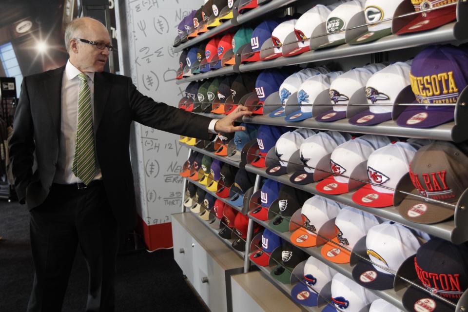 N.Y. Jets owner Woody Johnson inspects a New York Giants hat during the grand opening of the NFL Shop at Draft store, Monday, April 2, 2012 in New York. (AP Photo/Mary Altaffer)
