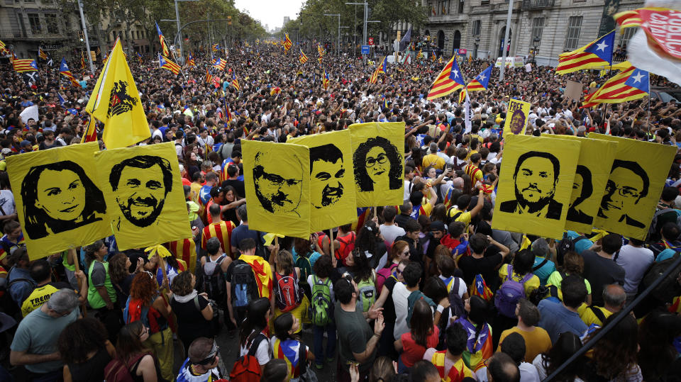 Protestors hold pictures of Catalan high-profile separatist politicians, some jailed and others who are fugitives from Spanish law after fleeing the country, during a demonstration in Barcelona, Spain, Friday, Oct. 18, 2019.The Catalan regional capital is bracing for a fifth day of protests over the conviction of a dozen Catalan independence leaders. Five marches of tens of thousands from inland towns are converging in Barcelona's center for a mass protest. (AP Photo/Emilio Morenatti)