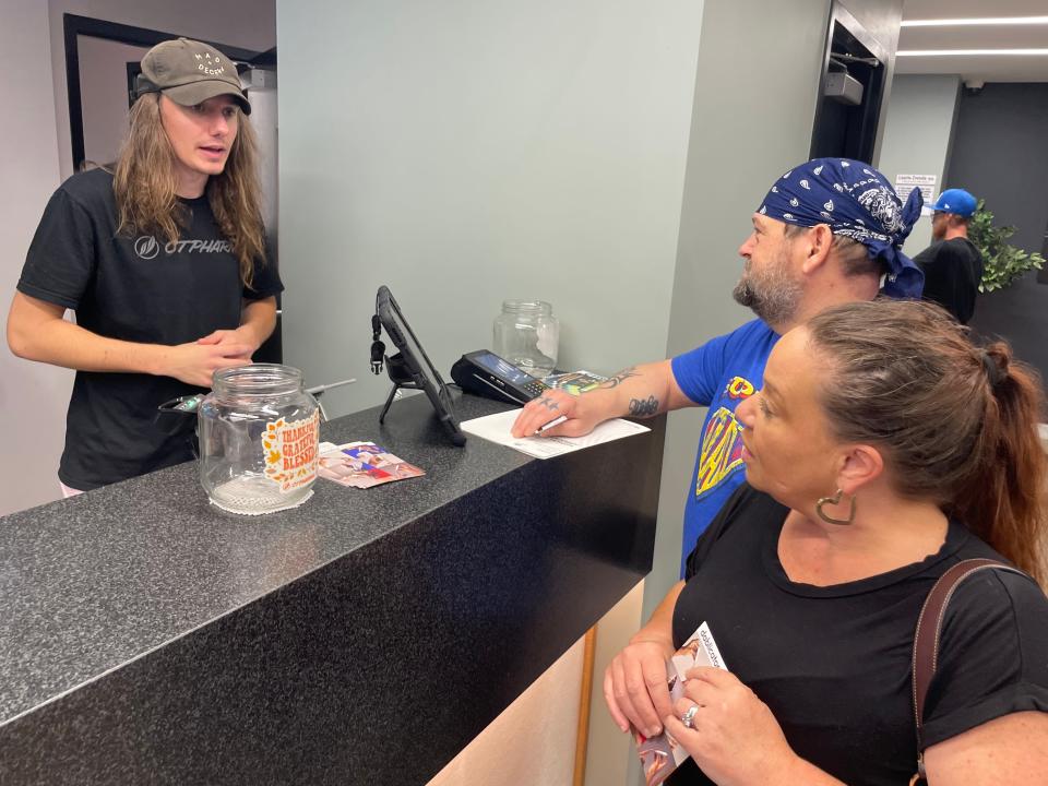 Michael Szaro, AIC Supervisor for Zen Leaf Norwich, helps Nelson and Bethany Pabon with their purchase.