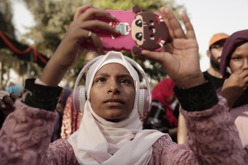 In this June 20, 2019 photo, a teenager films Sudanese dancers on her mobile phone during an event marking the U.N.'s International Refugee Day, in Cairo, Egypt. The Egyptian capital is home to hundreds of thousands of sub-Saharan African migrants, many who have fled deadly violence or dire poverty at home. But on the streets of Cairo, they face new dangers - harassment, abuse, and sometimes rape. (AP Photo/Maya Alleruzzo)