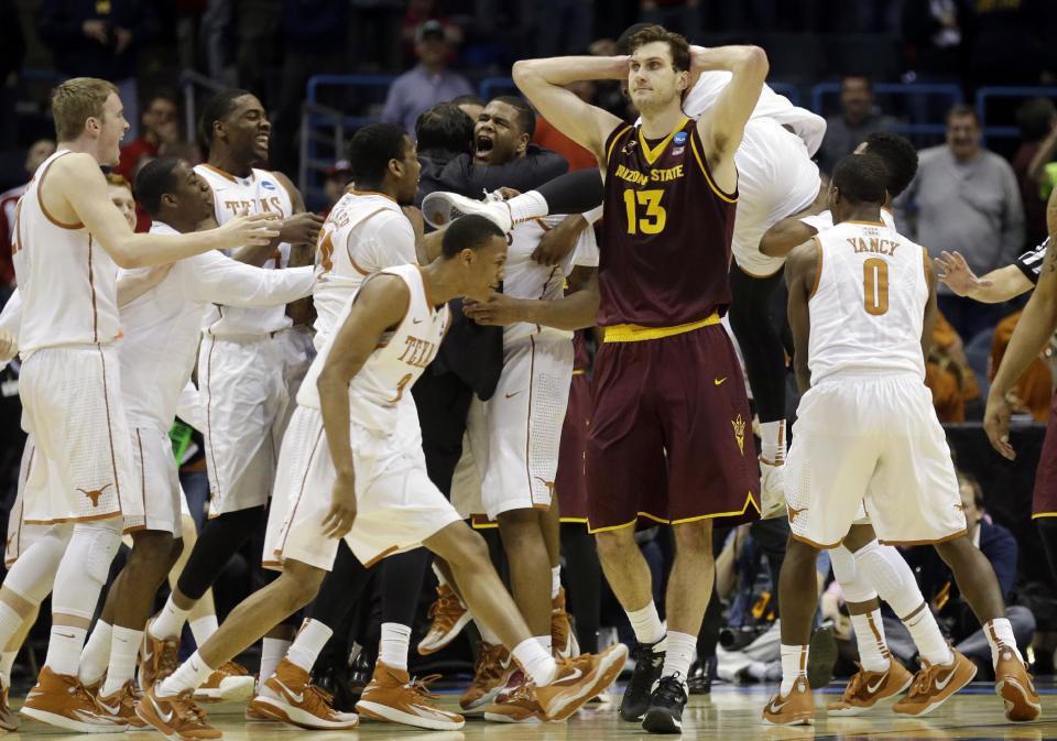 Texas players celebrates Cameron Ridley's game winning shot as Arizona State center Jordan Bachynski (13) walks off after a second-round game in the NCAA college basketball tournament Thursday, March 20, 2014, in Milwaukee. Texas won 87-85. (AP Photo/Jeffrey Phelps)