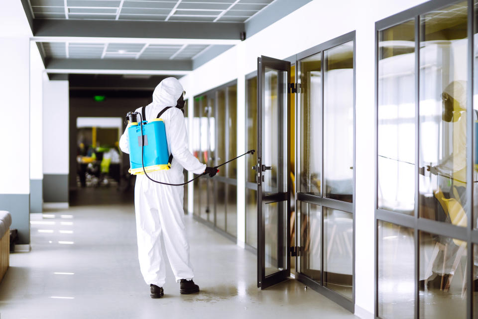 Disinfection of office to prevent COVID-19, Man in protective hazmat suit with with spray chemicals to preventing the spread of coronavirus, pandemic in quarantine city. Cleaning concept.