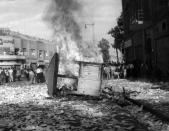 FILE - This Aug. 19, 1953 file photo shows a Communist newspaper kiosk burned by pro-shah demonstrators after the coup d'etat which ousted Prime Minister Mohammad Mossadegh, in Tehran, Iran. In 2018, as Iran deals with President Donald Trump's decision to pull America from the nuclear deal with world powers, more are invoking the 1953 CIA-backed coup that toppled Mossadegh as proof the U.S. cannot be trusted. (AP Photo, File)