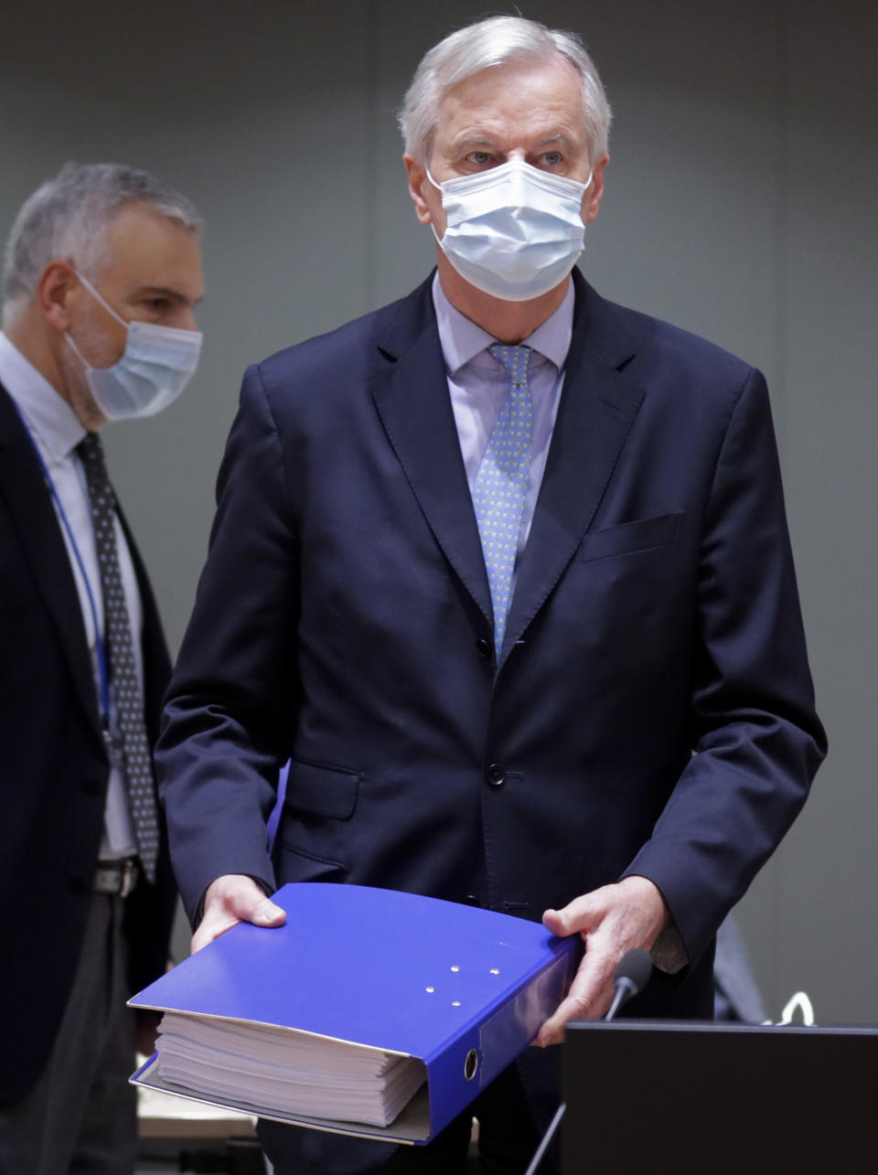 European Union chief negotiator Michel Barnier carries a binder of the Brexit trade deal during a special meeting of Coreper, at the European Council building in Brussels, Friday, Dec. 25, 2020. European Union ambassadors convened on Christmas Day to start an assessment of the massive free-trade deal the EU struck with Britain. After the deal was announced on Thursday, EU nations already showed support for the outcome and it was expected that they would unanimously back the agreement, a prerequisite for its legal approval. (Olivier Hoslet, Pool via AP)