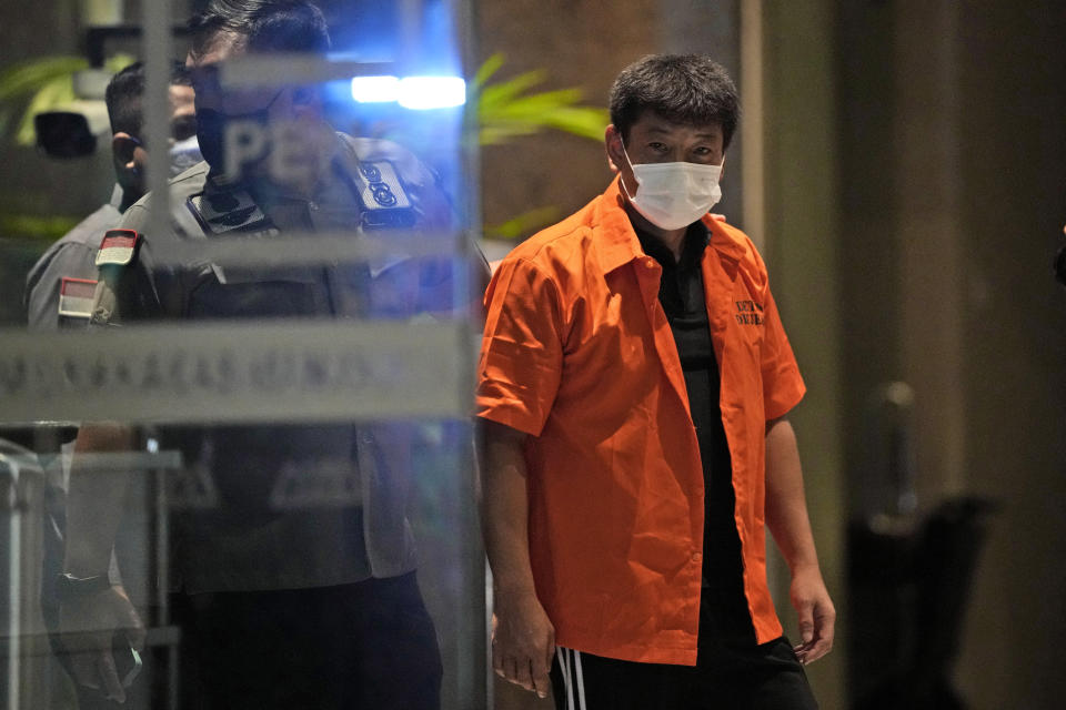 Immigration officers escort Japanese fugitive Mitsuhiro Taniguchi who was arrested on Sumatra island in early June, prior to his deportation in Jakarta, Indonesia, Wednesday, June 22, 2022. Indonesia on Wednesday deported Taniguchi who was wanted by Japanese police for COVID-19 subsidy fraud. (AP Photo/Dita Alangkara)