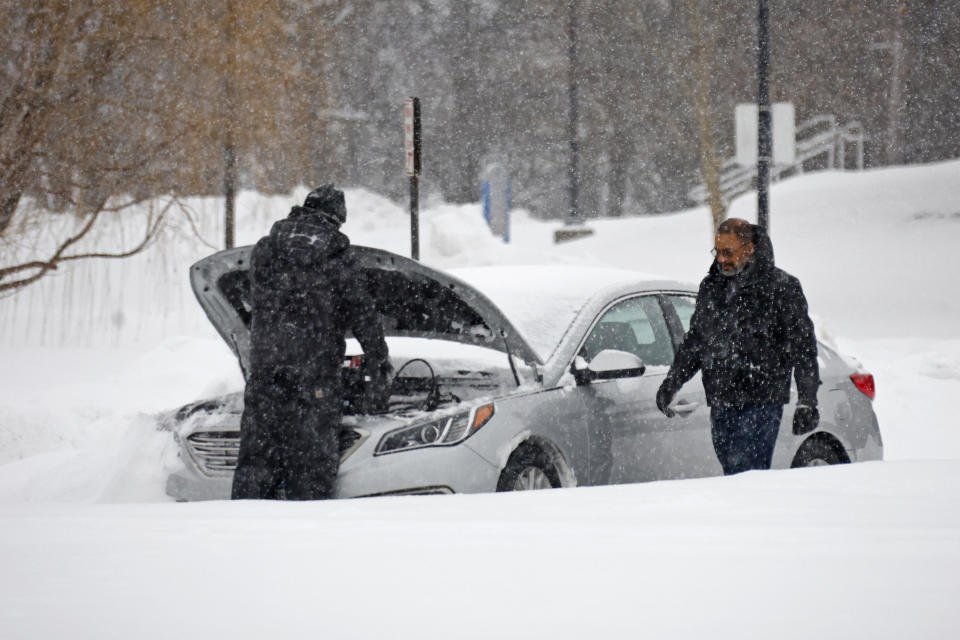 People attempt to get a car started after a winter storm rolled through Western New York Tuesday, Dec. 27, 2022, in Amherst, N.Y. (AP Photo/Jeffrey T. Barnes)