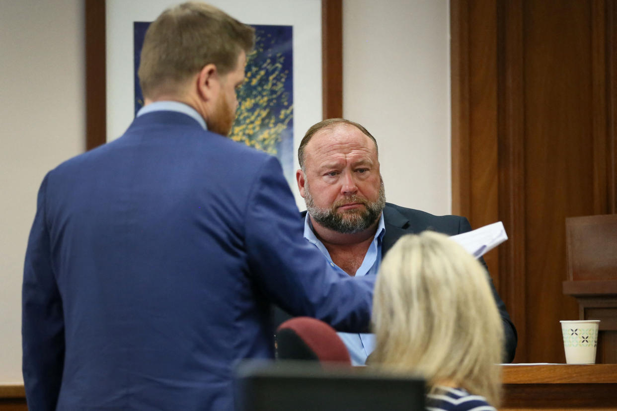 Mark Bankston shows a document to Alex Jones, who looks perplexed.