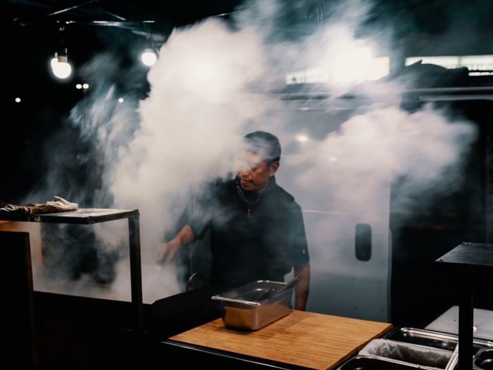 A man grilling meat at a taco stand in West Adams.