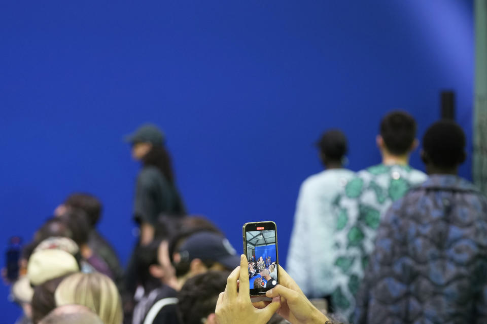 A man takes photos with his mobile phone during the Dhruv Kapoor men's and women's Spring Summer 2024 fashion show, unveiled during the Fashion Week in Milan, Italy, Monday, June 19, 2023. (AP Photo/Antonio Calanni)