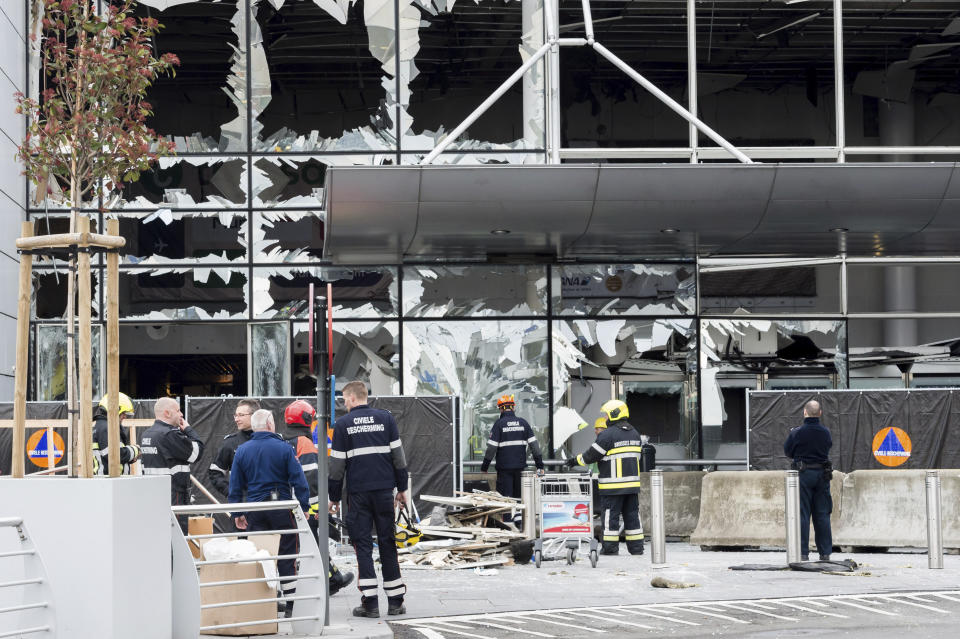 FILE - In this March 23, 2016 file photo, police and other emergency workers stand in front of the damaged Zaventem Airport terminal in Brussels. One year after the March 22, 2016 Brussels attacks, the city's physical scars may have healed, but the pain is still apparent beneath the surface. (AP Photo/Geert Vanden Wijngaert, Pool, File)