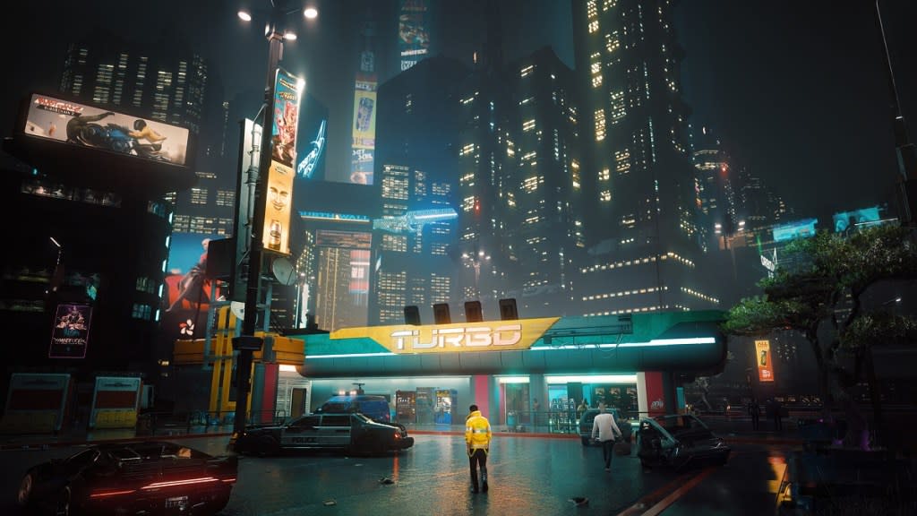 Cyberpunk 2077: a person in a yellow jacket looks insignificant against the neon buildings of Night City.