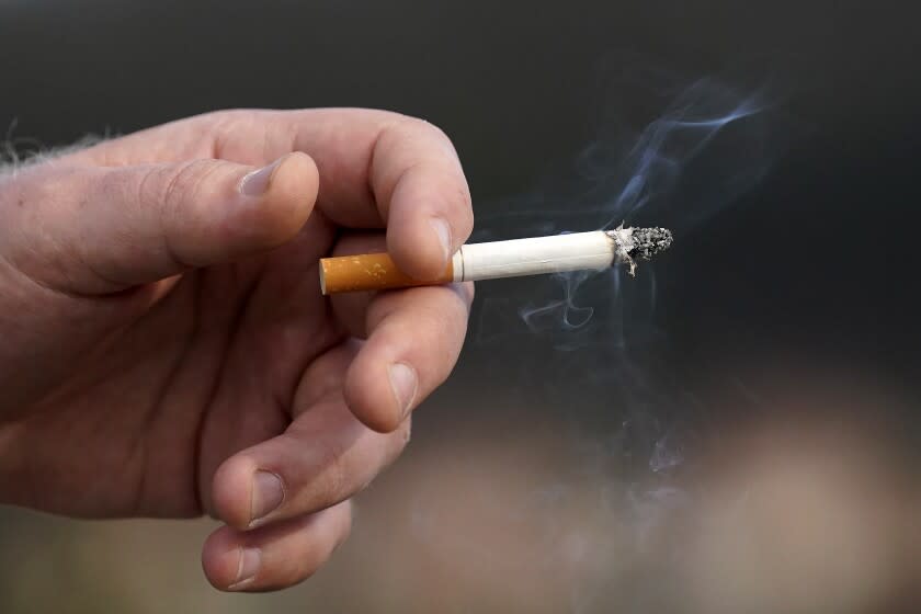 FILE - In this Dec. 2, 2020, file photo, a man who did not want to be identified holds a lit cigarette while smoking in San Francisco. San Francisco Supervisors rejected a cigarette smoking ban in San Francisco apartments a week after approving the proposal. The measure failed to get a second "yes" vote, usually considered a given before sending legislation on to the mayor for approval or a veto. (AP Photo/Jeff Chiu, File)