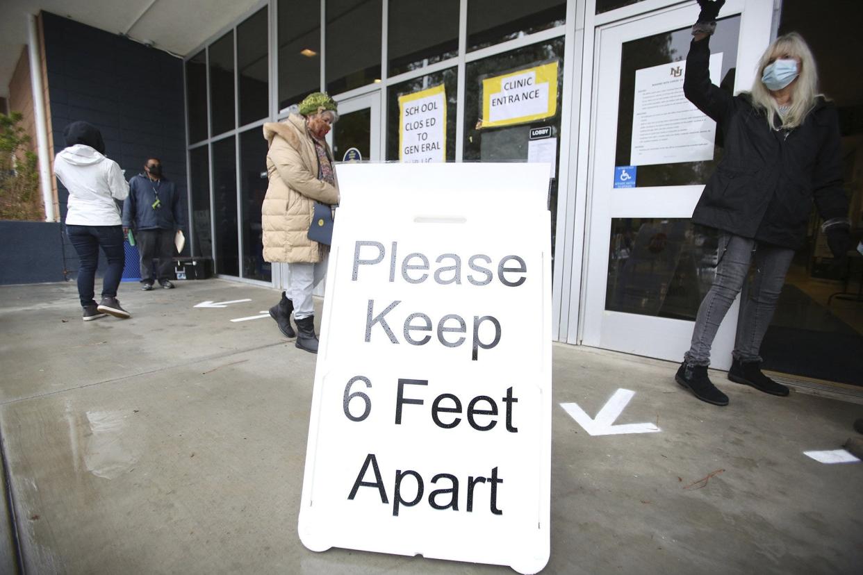 FILE - A sign asks those getting vaccinated to keep 6 feet apart during the vaccination event, Wednesday, Jan. 27, 2021, at Nevada Union High School in Grass Valley, Calif. The CDC revised its COVID guidelines Thursday, further relaxing quarantine recommendations and dropping the recommendation that people stay at least 6 feet away from each other. (Elias Funez/The Union via AP, File)