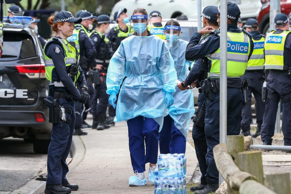 Medical staff wearing PPE walk past police at the estate (Getty Images)