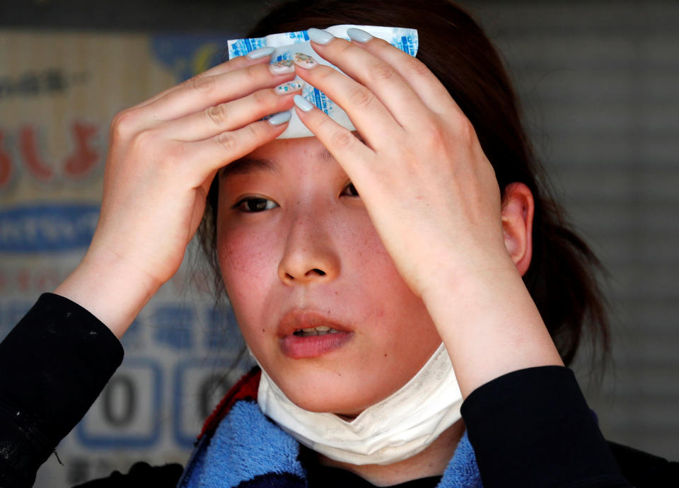 <p>A volunteer, for recovery work, uses a pack of refrigerant to a cool down as she takes a break in a heat wave at a flood affected area in Kurashiki, Okayama Prefecture, Japan, July 14, 2018. (Photo: Issei Kato/Reuters) </p>