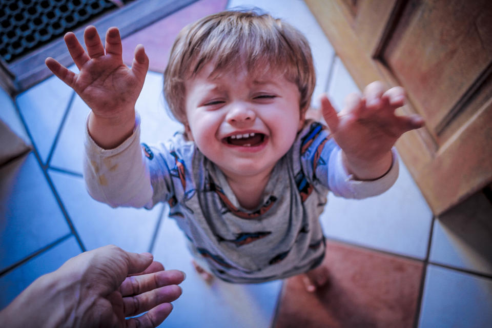 A photo looking down at an upset toddler - as if asking to be picked up.