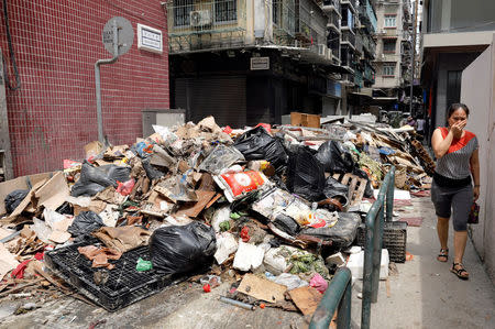 A woman covers her nose as she walks past debris after Typhoon Hato hits in Macau, China August 25, 2017. REUTERS/Tyrone Siu