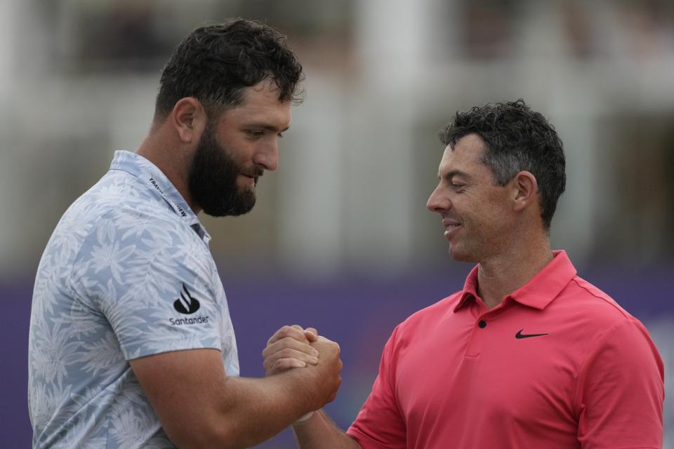 Rory McElroy from Northern Ireland, right, shakes hand with Jon Rahm from Spain after they finished the round one on the 18th hole during the DP World Tour Championship golf tournament, in Dubai, United Arab Emirates, Thursday, Nov. 16, 2023. (AP Photo/Kamran Jebreili)