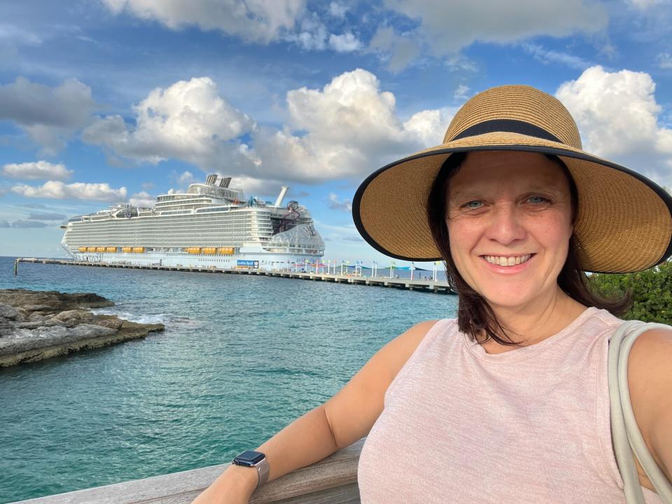kari posing for a selfie with a big cruise ship docked at port behind her