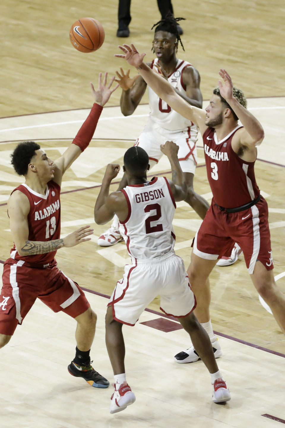 Oklahoma's Umoja Gibson (2) passes the ball to Victor Iwuakor (0) away from Alabama's Jahvon Quinerly (13) and Alex Reese (3) during the second half of an NCAA college basketball game in Norman, Okla., Saturday, Jan. 30, 2021. (AP Photo/Garett Fisbeck)