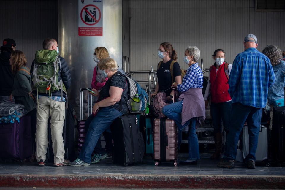 Travelers wait in line for a charter flight coordinated by the U.S. embassy at the La Aurora airport in Guatemala City, Monday, March 23, 2020. American citizens stranded abroad because of the coronavirus pandemic are seeking help in returning to the United States. (AP Photo/Moises Castillo)