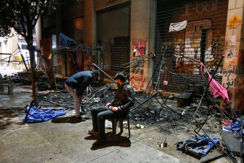 A man sits near burnt tents during a protest against a ruling elite accused of steering Lebanon towards economic crisis in Beirut