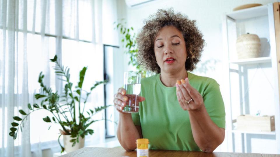 mature woman taking multivitamins alongside spironolactone for hair loss