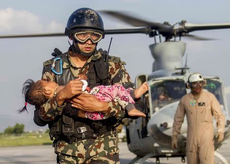 A Nepalese soldier carries a young victim who was hurt in a second earthquake, from a U.S Marine Corps UH-1Y Venom helicopter to a medical triage area at Tribhuvan International Airport, in Kathmandu, Nepal May 12, 2015. REUTERS/U.S. Marine Corps/Gunnery Sgt. Ricardo Morales/handout via Reuters