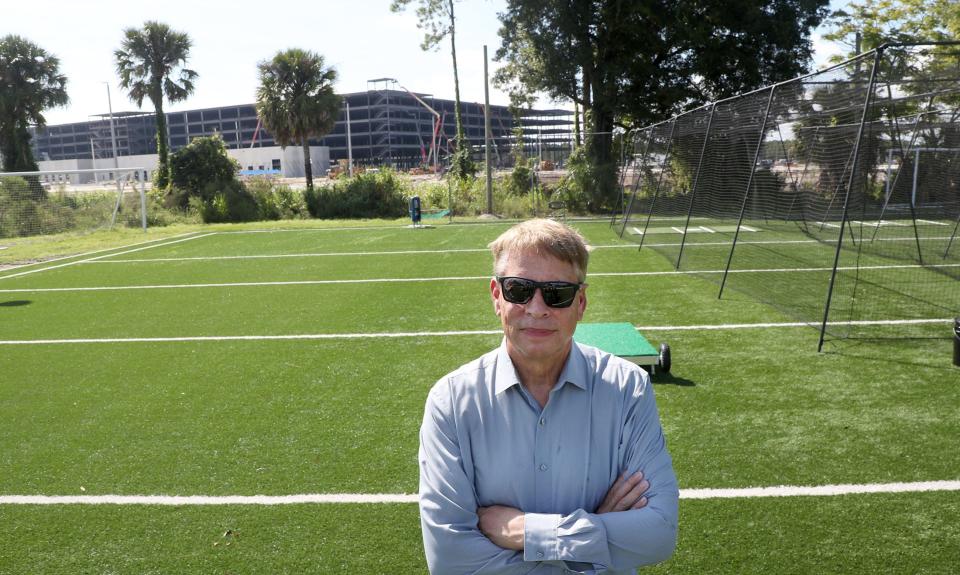 Mike Panaggio, owner of DME Sports Academy at 2441 Bellevue Ave. in Daytona Beach, stands on one of the sports training facility's soccer fields as his new neighbor, a five-story Amazon robotics fulfillment center under construction, looms behind him on Wednesday, Aug. 31, 2022.