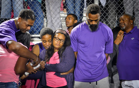 Shoshana Boyd (center L) and Olympic sprinter Tyson Gay (center R) stand surrounded by family and friends during a candlelight vigil at Lafayette High School for their daughter Trinity Gay, who died in an exchange of gunfire early Sunday morning, in Lexington, Kentucky. REUTERS/Bryan Woolston