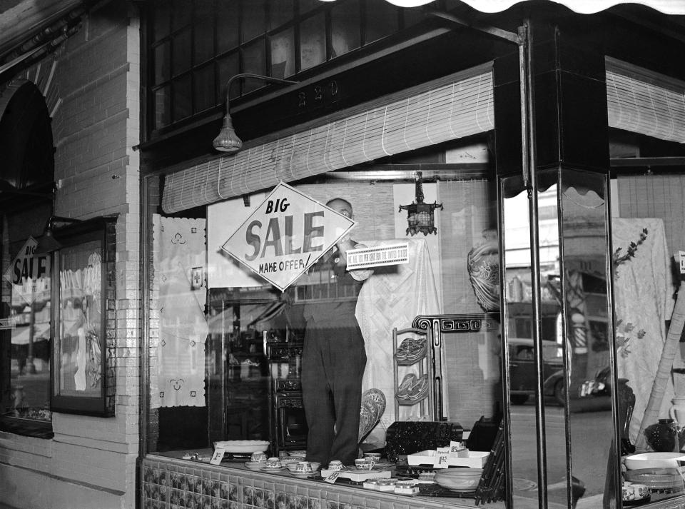 <p>Bargains, with articles marked down as much as 40 percent, were on everywhere in Los Angeles’ “Little Tokyo”, March 5, 1942, as its Japanese residents prepare to leave following the issuance of orders for the evacuation of enemy aliens and American-born Japanese from specified combat zones along the Pacific coast. T. Horiuchi, proprietor of one of the largest Asian art stores in the district, posts a sale sign in his window. Alongside is a sign declaring, “We are 100 percent for the United States.” (AP Photo) </p>